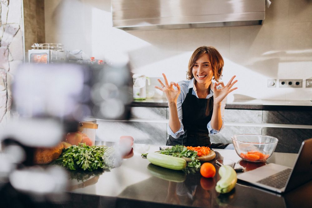 Chef presenting fresh vegetables while filming a cooking show in a home kitchen